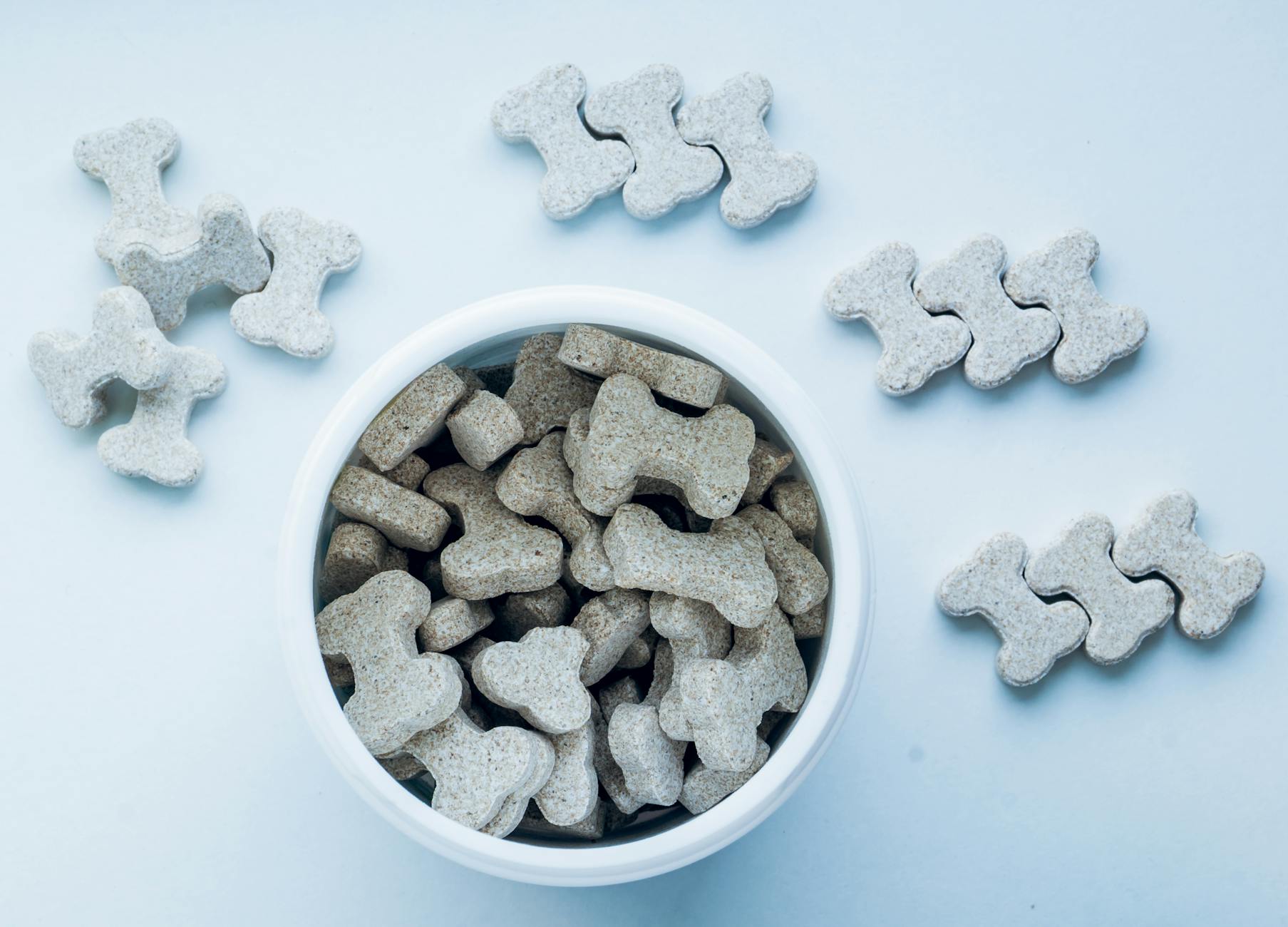Some crunchy dog treats in a bowl with bone shapes.